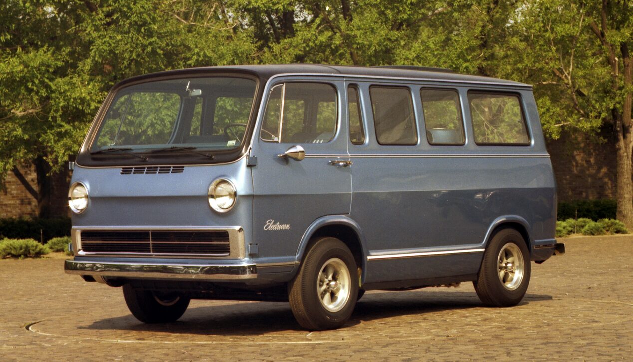 A 1966 Chevy Electrovan Parked on Grass in Front of Trees