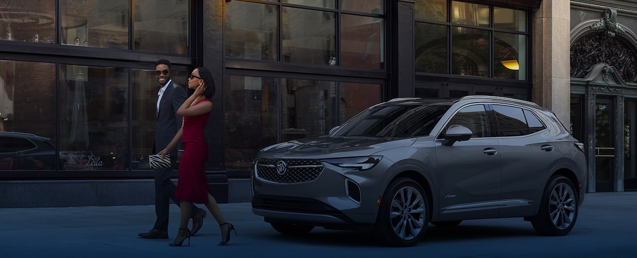 A Dressed-Up Couple Walking Away From Their Parked Buick In Front of a Building