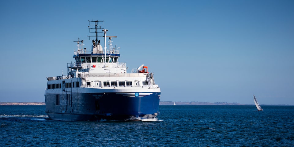 Front View of a Ship Sailing on Blue Ocean Water with a Sailboat in the Background